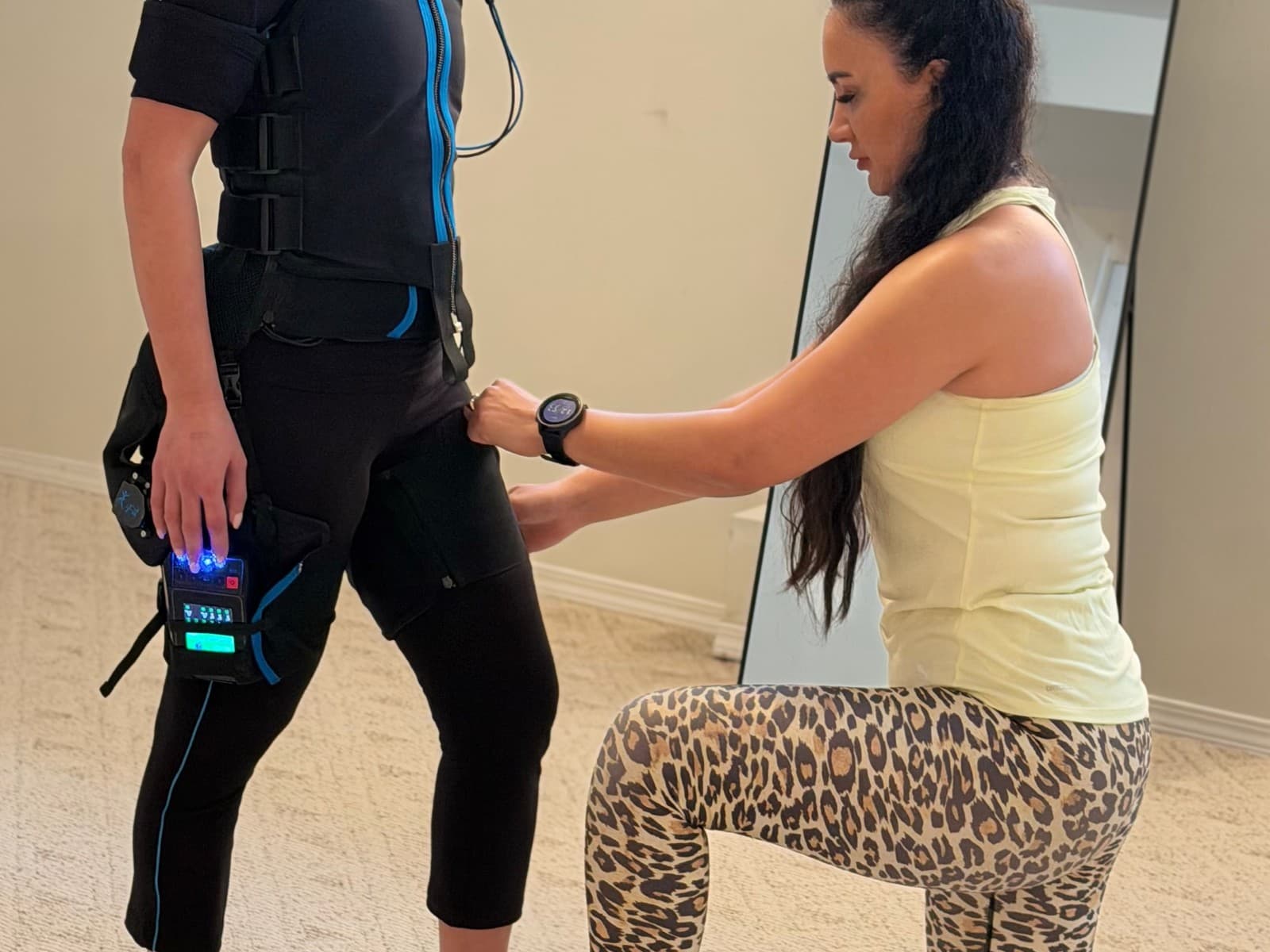 Mahnaz adjusting an EMS suit during a first-session setup.