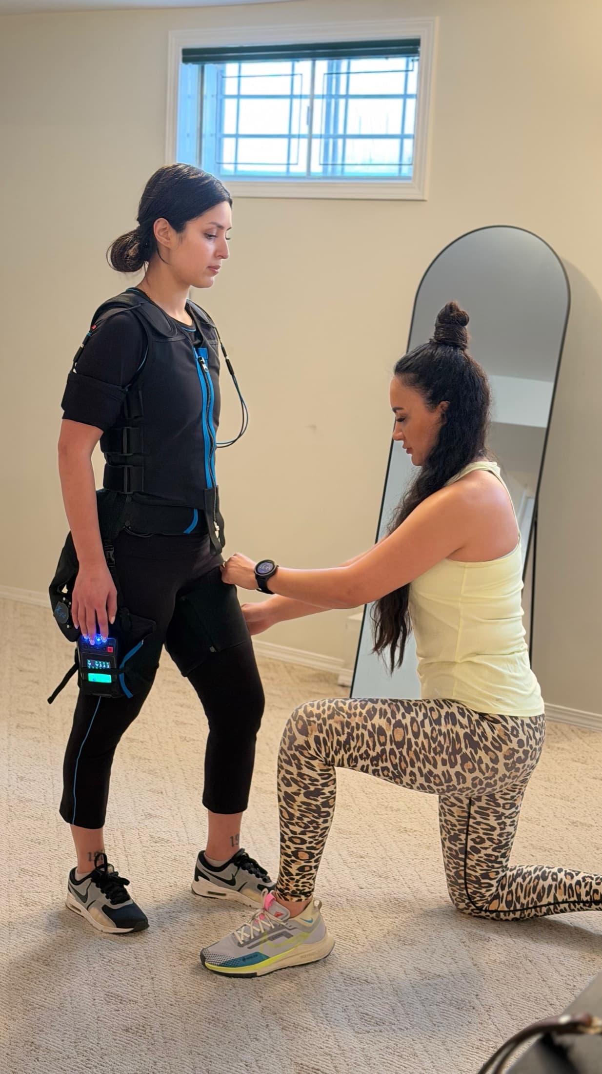 Coach adjusting an EMS training suit before a guided session.