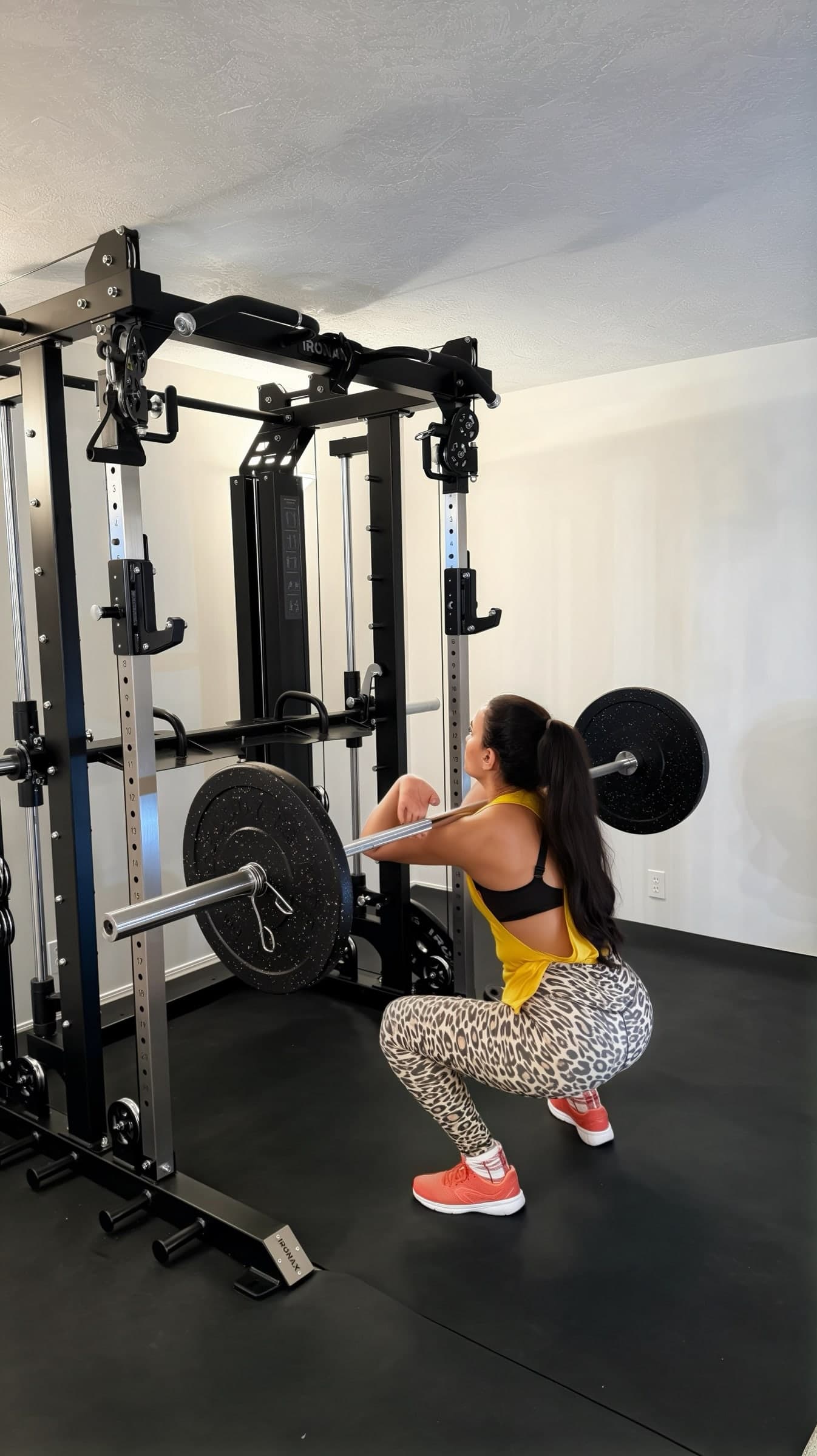 Client performing a barbell squat with a squat rack in a coached personal training session.